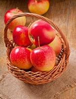 manzanas en una cesta sobre fondo de madera foto
