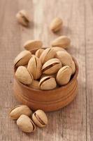 Cracked and Dried Pistachio Nuts In A Wooden Bowl photo