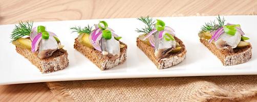 Sandwiches of rye bread with herring, onions and herbs. photo