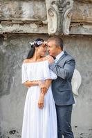 sesión de fotos de boda en el fondo del antiguo edificio. el novio mira a su novia posando. fotografía de boda rústica o boho.