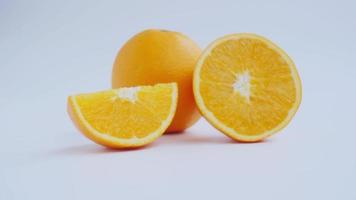 ingrandire per tagliare a metà e affettare un frutto arancione maturo con buccia giallo dorato. isolato su sfondo bianco con ombra. video