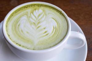 A cup of hot green tea with latte milk art. photo