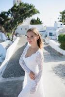 A girl in the white dress of the bride is facing the city. photo