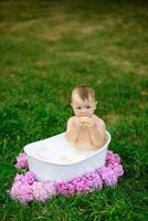 Little girl bathes in a milk bath in the park. The girl is having fun in the summer. photo