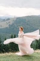 whirling bride holding veil skirt of wedding dress at pine forest photo