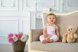The little one-year-old girl smiles and sits. photo