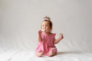 niña de 6 meses con un peine en la mano sobre un fondo blanco. foto