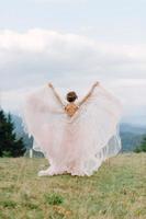 novia girando sosteniendo la falda del velo del vestido de novia en el bosque de pinos foto