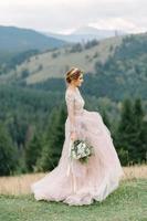 whirling bride holding veil skirt of wedding dress at pine forest photo