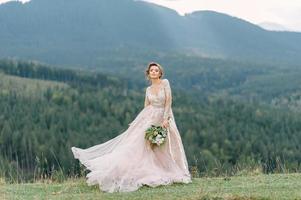 whirling bride holding veil skirt of wedding dress at pine forest photo