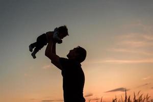 A father throws up his little daughter at sunset. photo