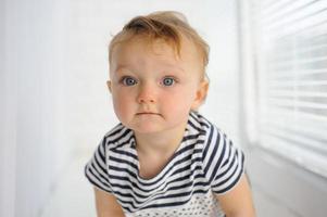 The little one-year-old girl smiles and sits. photo