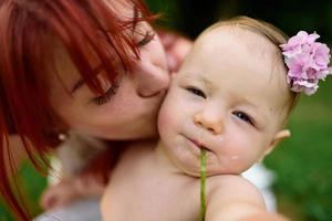 Mom hugs and plays with her one-year-old daughter wrapped in a towel after bathing. photo