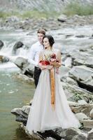 la novia y el novio. ceremonia de boda cerca de un río de montaña foto