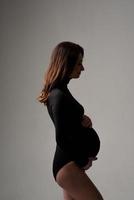 Young beautiful pregnant woman in black bodysuit and hat. photo