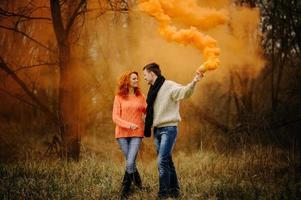 joven pareja feliz sosteniendo bombas de humo en el camping foto