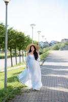 mujer embarazada con un sombrero posando con un vestido sobre un fondo de árboles verdes. foto