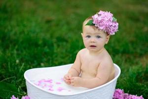 Little girl bathes in a milk bath in the park. The girl is having fun in the summer. photo