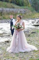 An attractive newlywed couple, a happy and joyful moment. A man and a woman shave and kiss in holiday clothes. Bohemian-style wedding cermonia in the forest in the fresh air. photo