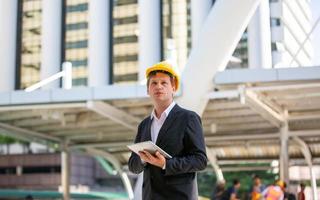 el ingeniero revisando el portapapeles en el edificio del sitio de construcción. el concepto de ingeniería, construcción, vida urbana y futuro. foto