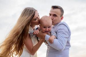 Father and mother lead their one-year-old son by the hand. photo