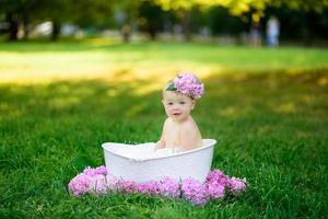 niña se baña en un baño de leche en el parque. la niña se está divirtiendo en el verano.