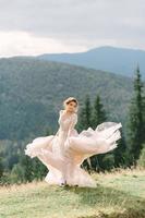 novia girando sosteniendo la falda del velo del vestido de novia en el bosque de pinos foto