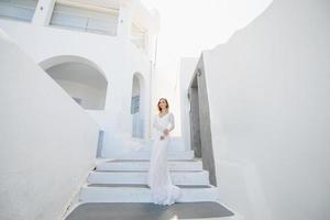 The beautiful blond hair young women bride blue in a wedding white long sexy dress on Santorini in Greece photo