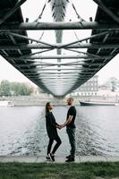 pareja joven enamorada parada en el puente colgante de la montaña abrazándose mirándose sonriendo foto