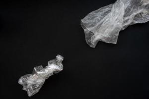 botella de plástico comprimida sobre un fondo negro. el concepto de salvar el medio ambiente. foto