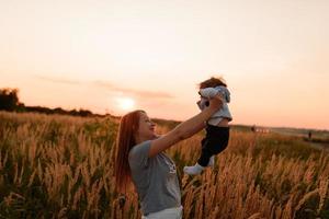 A mother walks in the field with her little daughter in her arms. photo