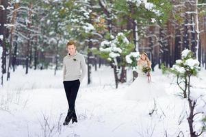 Bride and groom are sitting on the log in the winter forest. Close-up. Winter wedding ceremony.