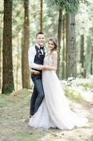 Attractive couple newlyweds, happy and joyful moment. Man and woman in festive clothes sit on the stones near the wedding decoration in boho style. Ceremony outdoors. photo