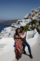 la pareja está sentada en el techo en santorini, abrazándose y riéndose foto