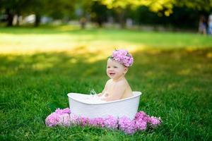 Little girl bathes in a milk bath in the park. The girl is having fun in the summer. photo