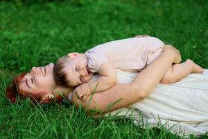 Mom hugs and plays with her one-year-old daughter wrapped in a towel after bathing. photo