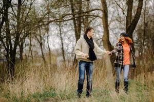 Young couple walks in autumn forest. Man giving his girlfriend piggyback. People having fun outdoors photo