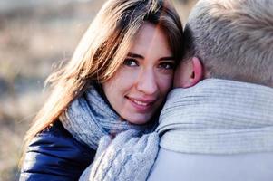 holidays, winter, christmas, hot drinks and people concept - happy couple in warm clothes hugging near the tree branches with snow photo