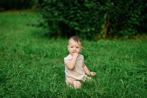 una niña de un año se sienta en el césped. foto