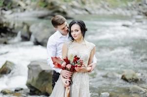 la novia y el novio. ceremonia de boda cerca de un río de montaña