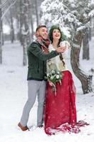 Beautiful bride and groom with a white dog are standing on the background of a snowy forest. photo