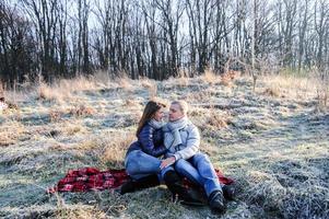 joven y bonita pareja sensual de moda enamorada sentada en un campo frío de invierno foto
