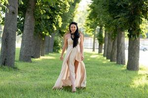 mujer embarazada con un sombrero posando con un vestido sobre un fondo de árboles verdes. foto