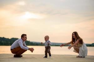 Father and mother lead their one-year-old son by the hand. photo