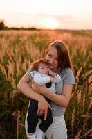 una madre camina por el campo con su hijita en brazos. foto