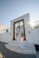 The beautiful blond hair young women bride blue in a wedding white long sexy dress on Santorini in Greece photo