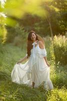 Pregnant woman in a hat posing in a dress on a background of green trees. photo
