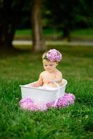 Little girl bathes in a milk bath in the park. The girl is having fun in the summer. photo