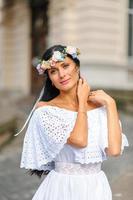 Wedding photo session on the background of the old building. The groom watches his bride posing. Rustic or boho wedding photography.