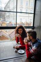 Happy and romantic couple in warm sweaters drink coffee from disposable paper cups in cafeteria. Holidays, christmas, winter, love, hot drinks, people concept photo